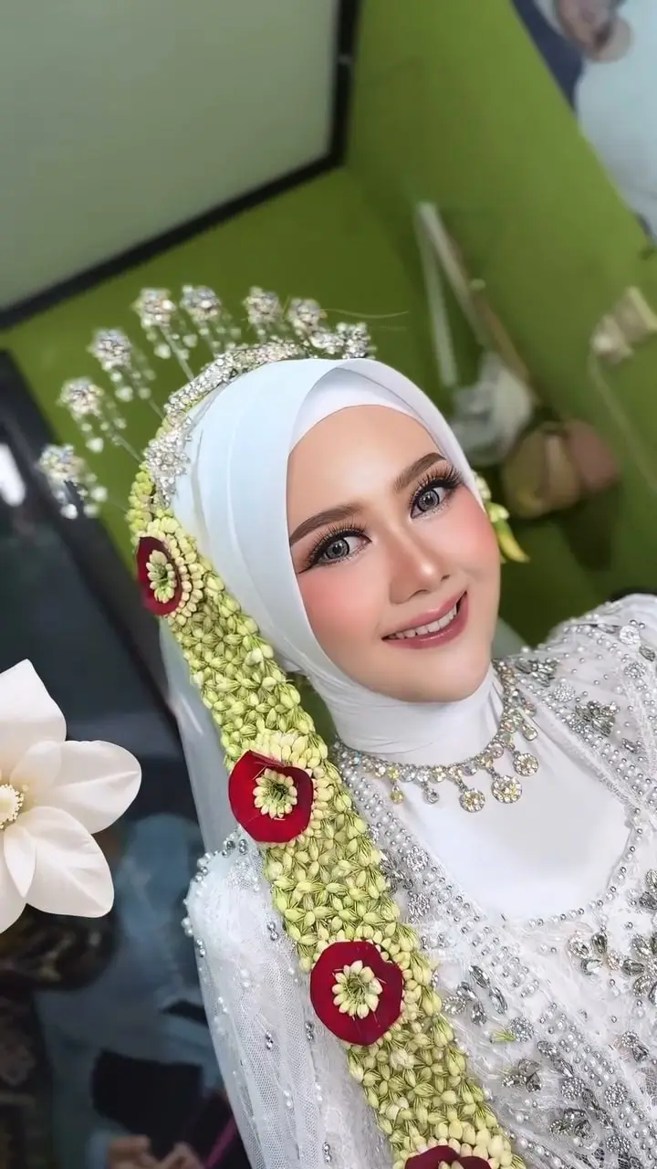 Putri tersenyum dengan makeup akad, siger perak, dan hijab putih