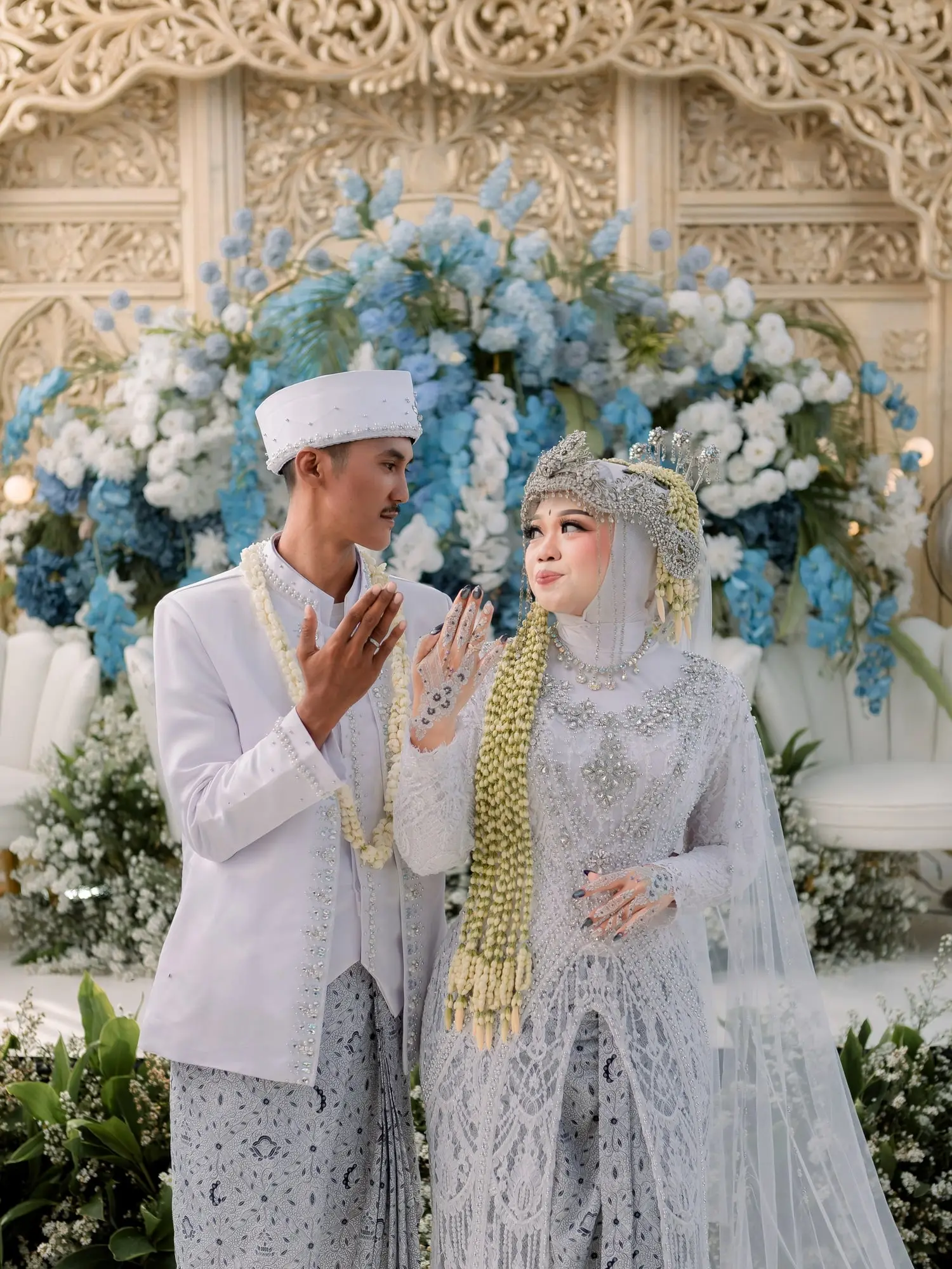 Pengantin Salsa dan Surya berbusana putih di depan pelaminan berbunga biru, makeup oleh Ala Makeup Gallery